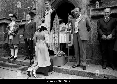 Josephine Isaac, die hübsche Maid von Holsworthy, ist 1975 die hübsche Maid. Sie ist gesegnet auf den Stufen der St. Peter- und St. Pauls-Kirche, bevor sie das St. Peters Fair eröffnet. Die Würdenträger des Dorfes stehen schweigend. Holsworthy, Devon, England, Juli 1975 UK 1970s HOMER SYKES Stockfoto