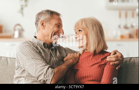 Fröhlich Reif Mann Umarmt Glücklich Frau Sitzen Zu Hause Stockfoto