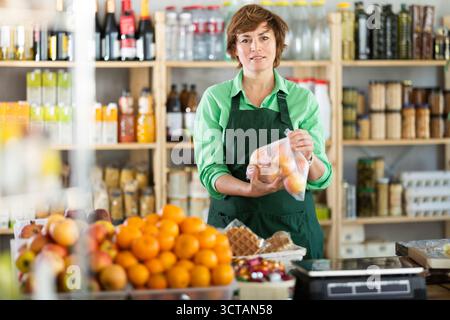 Erwachsene Frau Verkäufer bietet Mandarinen im Supermarkt an Stockfoto