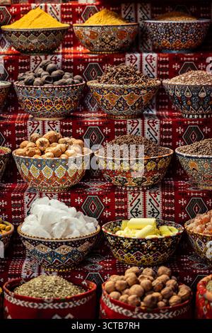 Ein exotisches und farbenfrohes Arrangement traditioneller omanischer Produkte zum Verkauf, darunter aromatische Kräuter, ganze Nüsse und Gewürzpulver. Stockfoto