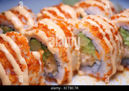 Bunte Sushi-Brötchen mit scharfer Sauce und knusprigen Stücken Stockfoto