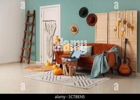 Inneneinrichtung mit stilvollem Wohnzimmer mit Sofa, Plattenspieler und Kürbissen Stockfoto