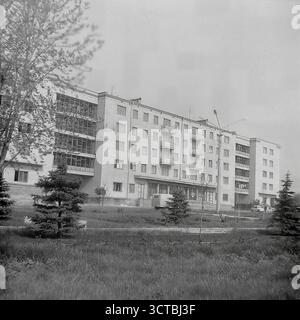 Ein neu fertiggestelltes fünfstöckiges Apartmentgebäude in einem neuen Wohnviertel von Sloviansk, ukrainische SSR, in den 1960er Jahren Das Foto zeigt eine spätere Generation von Chruschtschjowka, ein Kennzeichen des sowjetischen Massenwohnungsprogramms. Dieser architektonische Stil verfügt über eine Backsteinkonstruktion und große, mehrstöckige, verglaste Loggien oder Treppenhäuser, die zu dieser Zeit ein modernes Designelement waren. Die Landschaft ist immer noch frisch und vor dem Gebäude sind junge Tannen gepflanzt. Dieses Bild repräsentiert das Endprodukt des Bauboom der Epoche und das Versprechen eines modernen Lebens Stockfoto