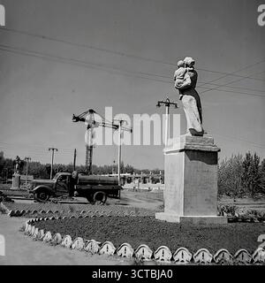 Der Bau des Puschkin Boulevard (heute Schewtschenko Boulevard) in Sloviansk, ukrainische SSR, in den 1960er Jahren Diese Fotos zeigen die Schaffung eines neuen öffentlichen Raumes mit Statuen des sozialistischen Realismus, die auf einer aktiven Baustelle installiert sind. In neu geformten Blumenbeeten stehen Denkmäler, die die idealisierte sowjetische Jugend und Mutterschaft darstellen, während im Hintergrund ein großer Turmkran arbeitet. Diese Gegenüberstellung von fertiger Kunst und roher Konstruktion war typisch für diese Zeit und symbolisierte die ideologischen Grundlagen, die für die neue Stadt gelegt wurden Stockfoto