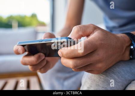 Mann mit Smartphone, Nahaufnahme. Männliche Hände halten das Smartphone und spielen im Freien mobile Spiele. Konzept von Technologie, digitalem Entertainment und gadge Stockfoto