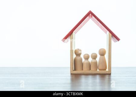 Familienpflege, Schutz und Versicherungskonzept. Holzpuppen Familie und ein Haus. Kopierbereich für Text. Stockfoto