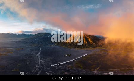 Aus der Vogelperspektive des Bromo Tengger Semeru Nationalparks, wo die Sonne die Vulkangipfel unter den wirbelnden Wolken küsst und eine dramatische Landschaft schafft: Mt Stockfoto