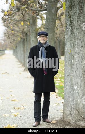 Älterer Mann, Rentner, mit schwarzem Mantel und Mütze im Park Stockfoto