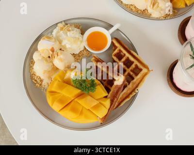 Genießen Sie ein köstliches Mango-Waffelfrühstück, das perfekt mit Eiscreme kombiniert wird Stockfoto