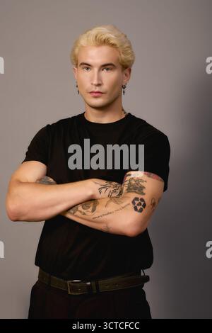 Ein stilvoller Teenager steht selbstbewusst mit gekreuzten Armen in einem modernen Ambiente. Stockfoto