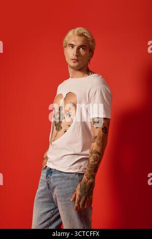 Gutaussehender Teenager steht selbstbewusst in einem trendigen Outfit und hebt Jugendkultur und Kunstfertigkeit hervor. Stockfoto