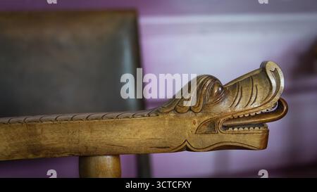 Detailreiche Schnitzerei eines Drachenkopfes an der Armlehne eines Holzstuhls, historischer Bauernhof und Pilgerunterkunft Budsjord, Dovre, Pilgerweg Stockfoto
