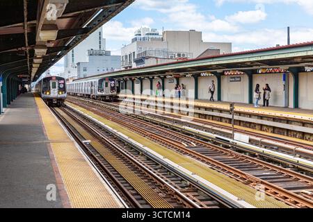 Zug J nähert sich dem Bahnsteig in der Hewes Street, New York City Stockfoto
