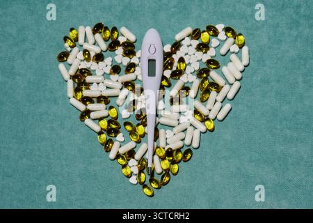 Medizinische Pillen und Thermometer in Herzform angeordnet, symbolisieren die Liebe und Pflege für die Gesundheit, fördern Wohlbefinden und einen gesunden Lebensstil Stockfoto