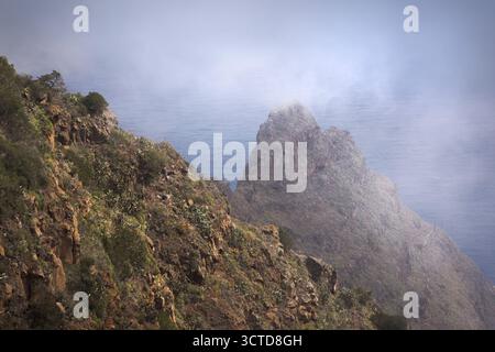 Steile Klippen ragen über das Meer, teilweise in Nebel gehüllt, und zeigen La Gomeras natürliche Schönheit. Stockfoto