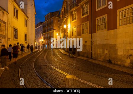 Alfama-Viertel in Lissabon bei Nacht in Portugal. Largo Santa Luzia Kopfsteinpflasterstraße mit Straßenbahnlinie der berühmten Straßenbahnlinie Nr. 28. Stockfoto