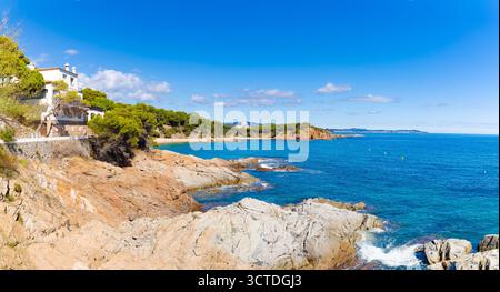 Die felsige Küste des Camino de Ronda in S’Agaró führt zum Strand Sa Conca mit Kiefern, türkisfarbenem Wasser und weißen Häusern im Mittelmeer. Stockfoto
