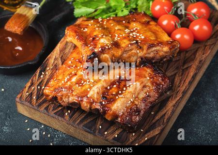 Scharfe heiße gegrillte Spare Ribs vom Sommer-BBQ serviert mit heißem Chili und frischen Tomaten Stockfoto