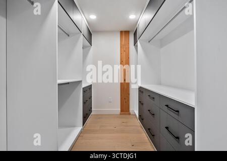 Großer begehbarer Kleiderschrank mit weißen Wänden und schwarzen Schubladen. Der Schrank ist sehr geräumig und hat viel Stauraum Stockfoto