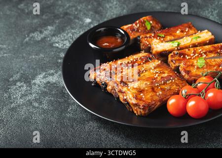 Heiße gegrillte Spare Ribs von einem Sommer BBQ serviert auf einem Teller mit Sauce. Draufsicht. Kopierbereich Stockfoto