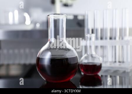 Glaskolben mit roter Flüssigkeit auf dem Tisch im Labor, Nahaufnahme Stockfoto