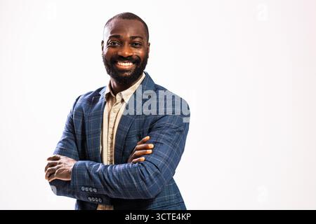Porträt eines glücklichen und erfolgreichen afroamerikanischen Geschäftsmannes. Der schwarze Mann im Business-Anzug steht mit überkreuzten Armen und lächelt. Stockfoto