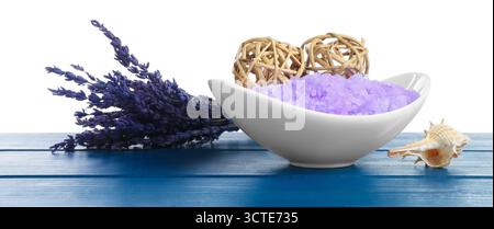 Violettes Meersalz in Schüssel, Lavendel und Schale auf blauem Holztisch vor weißem Hintergrund Stockfoto