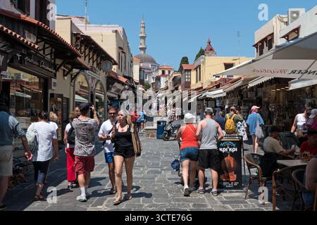 Blick auf die Altstadt von Rhodos, Griechenland mit Menschen, Wahrzeichen und alten Gebäuden. Touristen, die im Sommer Urlaub in der griechischen mittelalterlichen Stadt genießen. UNESCO Stockfoto