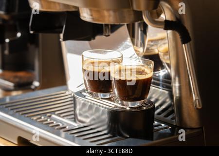 Zwei Gläser frisch gebrühten Espresso-Kaffee mit Crema-Schicht, hergestellt von einer Espresso-Maschine aus Edelstahl Stockfoto