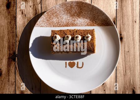 Blick von oben auf Mocha-Tiramisu-Brötchen, serviert auf einem weißen Teller mit „I Love You“-Dekor, kombiniert reichhaltigen Kaffeegeschmack mit romantischer Präsentation Stockfoto