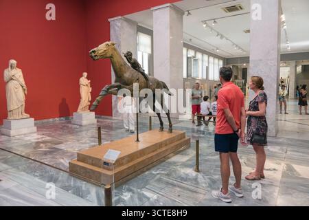 Innenansicht des Nationalen Archäologischen Museums von Athen, Griechenland mit Touristen und der antiken griechischen Statue des Jockeys von Artemision Stockfoto