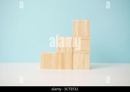 Natürliche Holzblöcke, die gestapelt sind, um Fortschritt, Gleichgewicht und Organisation anzuzeigen, mit einer minimalistischen Komposition, die ästhetischen Wert verleiht. Stockfoto