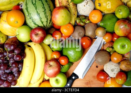 Exotische Früchte mischen sich mit Mangoborange und Ananas. Messer und Schneidebrett. Stockfoto