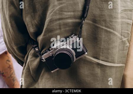 Eine klassische Kamera hängt um den Hals einer Person und unterstreicht die Liebe zu Fotografie, Erkundung und den flüchtigen Momenten des Lebens. Stockfoto