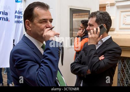 Bukarest, Rumänien. 6. Oktober 2025: Ludovic Orban (L) wurde heute, am 6. Oktober 2025, offiziell vom rumänischen Präsidenten Nicusor Dan (R) zum Präsidenten für Innenpolitik ernannt. - AKTENFOTO: (Bukarest, Rumänien. 25. April 2024) Nicusor Dan (R), Bürgermeister von Bukarest, spricht am Telefon, während Ludovic Orban (L), Präsident der Force of the Right (FD), seine Zigarette raucht. Nicusor legt seine Kandidatur für eine zweite Amtszeit als Generalbürgermeister von Bukarest beim Wahlbüro des Wahlkreises Bukarest vor. Quelle: Lucian Alecu/Alamy Live News Stockfoto