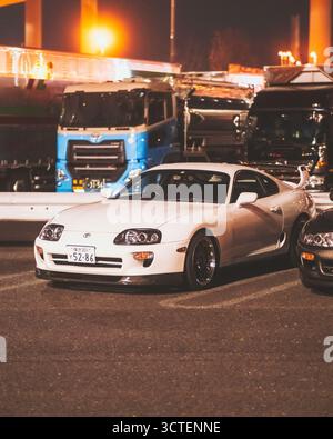 Yokohama, Japan - 27. Februar 2025: Blick auf einen strahlend weißen Toyota Supra, der auf dem Daikoku-Parkplatz unter dem sanften Schein der Straßenlaternen geparkt ist. Stockfoto