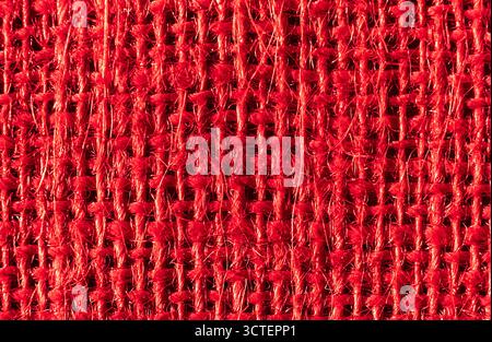 Makrodetail aus grobem rotem Gewebe mit Garnen, Webmuster und haptischer Textur für textilen Hintergrund. Nahaufnahme der roten Sackleinen Stockfoto