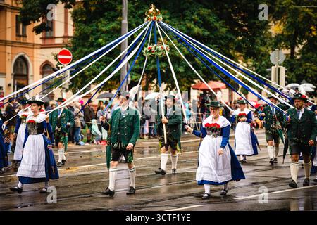 München, Deutschland - 18. September 2022: Blick auf eine traditionelle Oktoberfestparade mit lebhaften Kostümen, der Maypole und festlichem Geist vor der städtischen Kulisse. Stockfoto