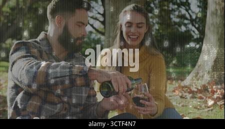 Rotwein aus der grünen Flasche in das Stängelglas gießen, Paare sitzen auf karierter Decke im Park Stockfoto