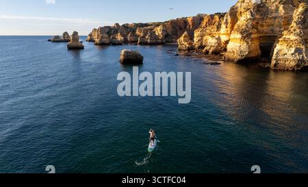 Portugal, Algarve. Klippen und Meer, von oben aus der Vogelperspektive auf Leute, die Paddelbrettsup machen Stockfoto