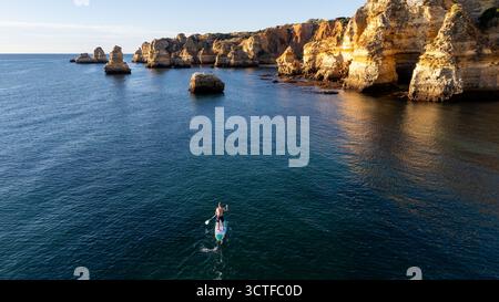 Portugal, Algarve. Klippen und Meer, von oben aus der Vogelperspektive auf Leute, die Paddelbrettsup machen Stockfoto