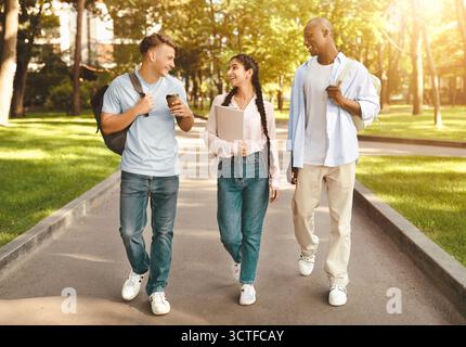 Drei multirassische High-School-Studenten gehen nach dem Studium und sprechen auf dem Universitätscampus im Freien Stockfoto