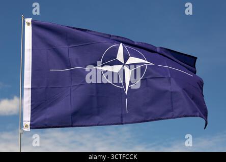 Dunkelblaue Flagge der NATO winkt gegen klaren Himmel Stockfoto