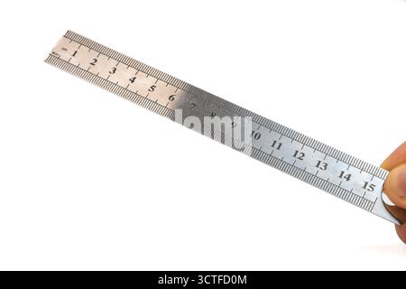 Hand hält ein Lineal aus Edelstahl auf isoliertem weißem Hintergrund. 15 cm Metalllineal in der Hand. Präzisionsmesswerkzeug für Länge und Zeichnung. Nahaufnahme Stockfoto