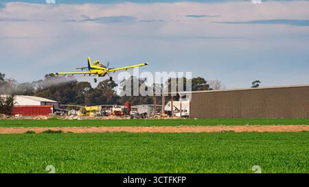 Yarrawonga, Victoria, Australien - 25. August 2025: Drucklufttraktor sprüht Erntegut neben Schuppen und Maschinen auf dem ländlichen Grundstück von Yarrawonga Stockfoto