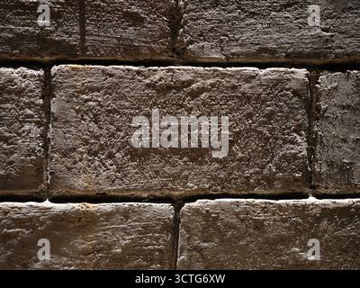 Nahaufnahme einer alten strukturierten Ziegelwand mit rauen, verwitterten Oberflächen Stockfoto
