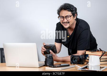 Ein junger freischaffender Fotograf arbeitet gern von zu Hause aus, umgeben von seiner Kamera und seinem kreativen Setup. Stockfoto
