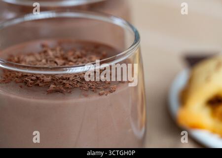 Köstliche hausgemachte Plätzchen serviert mit Schokoladenpudding in Glasbechern, garniert mit geriebener dunkler Schokolade. Gemütliche Dessertkomposition auf Holztisch Stockfoto