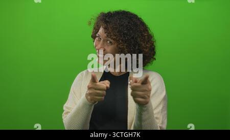 Eine hispanische Frau mittleren Alters zeigt mit den Zeigefingern direkt auf die Kamera auf dem grünen Bildschirm des Studios; Ermutigung. Stockfoto