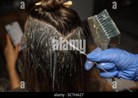Haarfärbeprozess, bei dem Frauen dunkles Haar in einer häuslichen Umgebung mit Liebe zum Detail und zur Pflege gefärbt werden Stockfoto